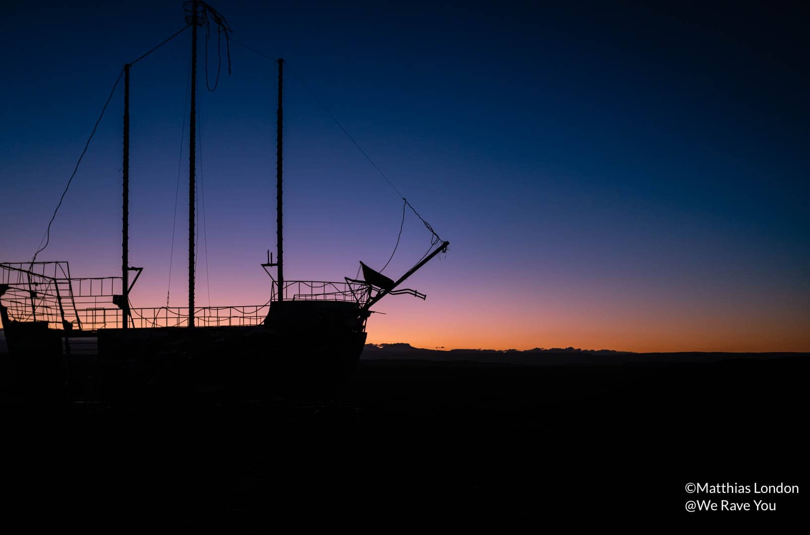 Return to the Source: Installation of a shipwreck in silhouette as photographed against the late-stage sunset.